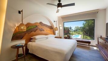 A bedroom with a large bed, a ceiling fan, a view of a swimming pool, and a wooden headboard.