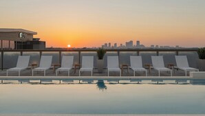 A rooftop pool with lounge chairs and a city skyline at sunset. - Aloft by Marriott Tampa Midtown (Tampa)