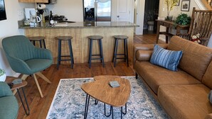 Una cocina moderna con armarios de madera, un refrigerador de acero inoxidable y una zona de bar con taburetes.