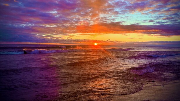 A sunset over the ocean with waves approaching the shore. - Spacious Cottage Close to Beach (Lexington)