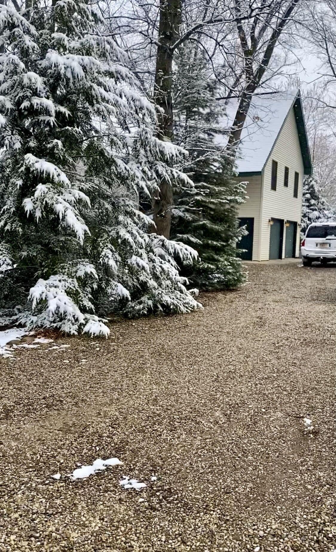 Una casa con techo inclinado y camino de entrada de grava.