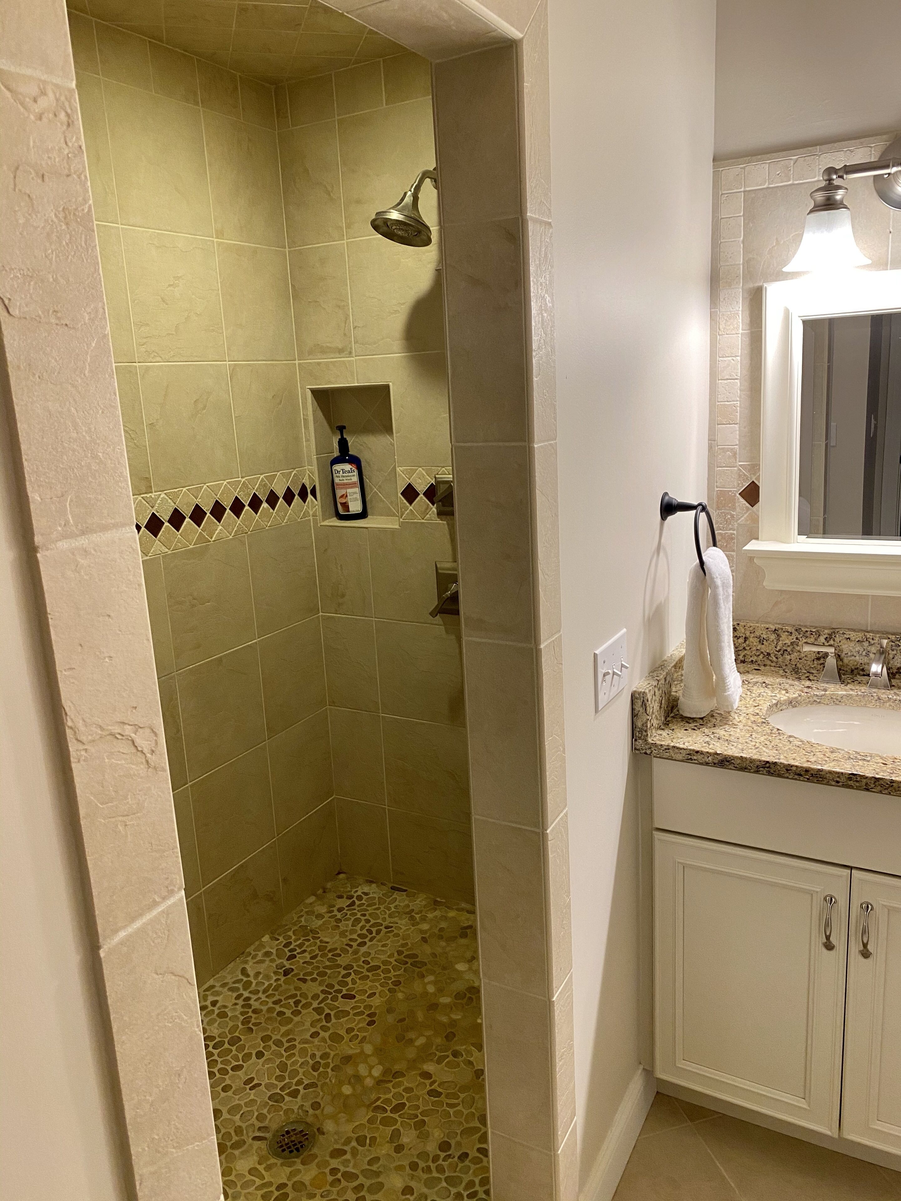 Ein Badezimmer mit Dusche, Waschbecken und Spiegel.