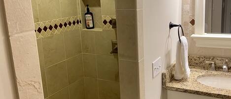 Ein Badezimmer mit Dusche, Waschbecken und Spiegel.