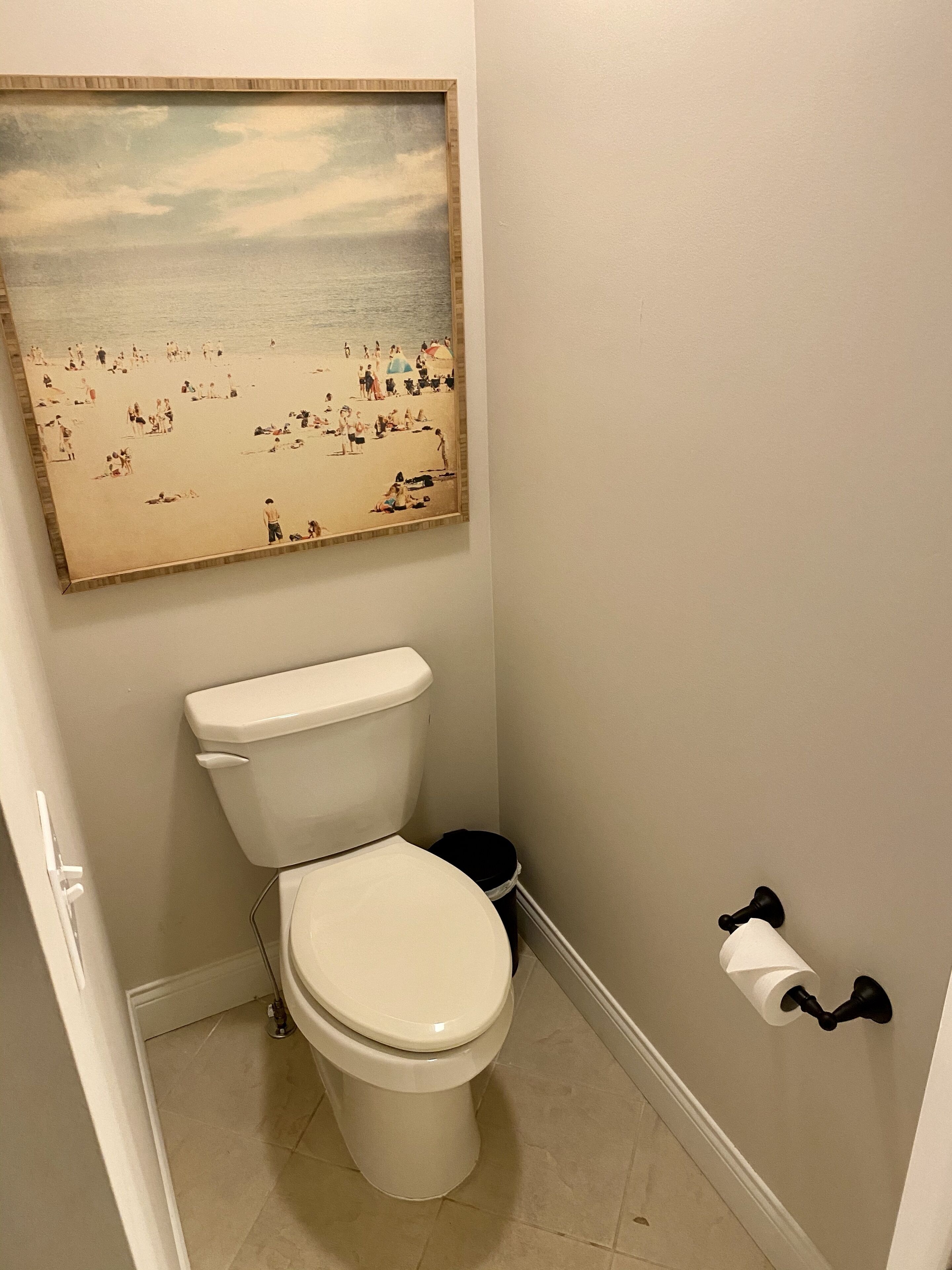 Une salle de bain équipée de toilettes, d’une poubelle et d’un porte-rouleau de papier toilette fixé au mur.
