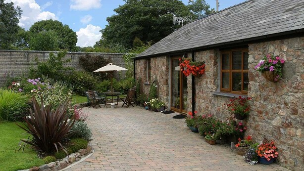 A stone building with a brick patio, outdoor seating, and potted flowers.