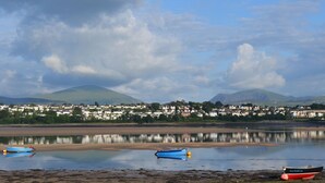 A coastal town with boats on the shore and mountains in the background.
