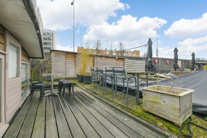 A rooftop terrace with outdoor seating, a planter box, and a view of the cityscape. - unique experience in Amsterdam on the water (Amsterdam)
