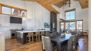 Una cocina amplia con una isla grande, suelo de madera y un comedor con sillas modernas.