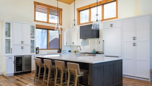 Una cocina moderna con una isla grande, taburetes de bar y suelo de madera.