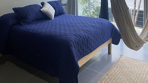 A bedroom with a large bed, a macrame wall hanging, a ceiling fan, and a hammock. - Beautiful and comfortable apartment in the Mayan jungle.  (Tulum)
