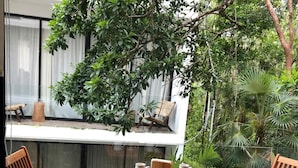 A wooden table with two chairs, a small wooden table, and two pitchers on the balcony. - Beautiful and comfortable apartment in the Mayan jungle.  (Tulum)