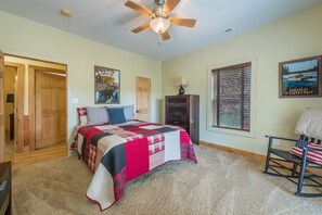 A bedroom with a bed, a ceiling fan, a wooden door, a window with blinds, and a framed picture on the wall. - Fire Pit & Fireplace~Mtn View~Grill & WiFi (Spruce Pine)