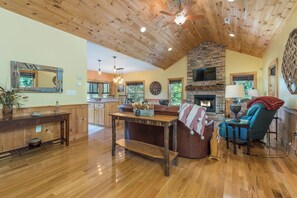 A spacious living area with a wooden ceiling, a stone fireplace, and a comfortable seating arrangement.