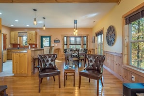 A spacious room with a wooden floor, a dining area with a table and chairs, and a kitchen area with wooden cabinets and a window.