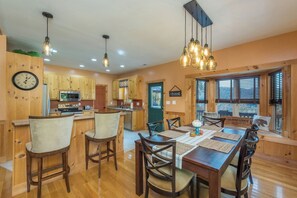A wooden interior with a dining area, kitchen, and a sign indicating 'Pine Lodge.' - Fire Pit & Fireplace~Mtn View~Grill & WiFi (Spruce Pine)