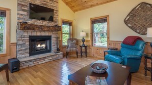 Una sala acogedora con chimenea de piedra, techo de madera y sofá de cuero azul.