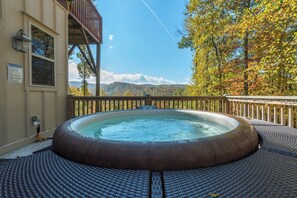 Een hottub op een terras met uitzicht op bergen en herfstkleuren.