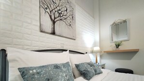 A bedroom with a bed, pillows, a nightstand, a lamp, a mirror, and a wall art piece. -  Cute & luxury suite with patio, just few steps away from beach , nearby Delphi (ΙΤΕΑ- ΚΙΡΡΑ)