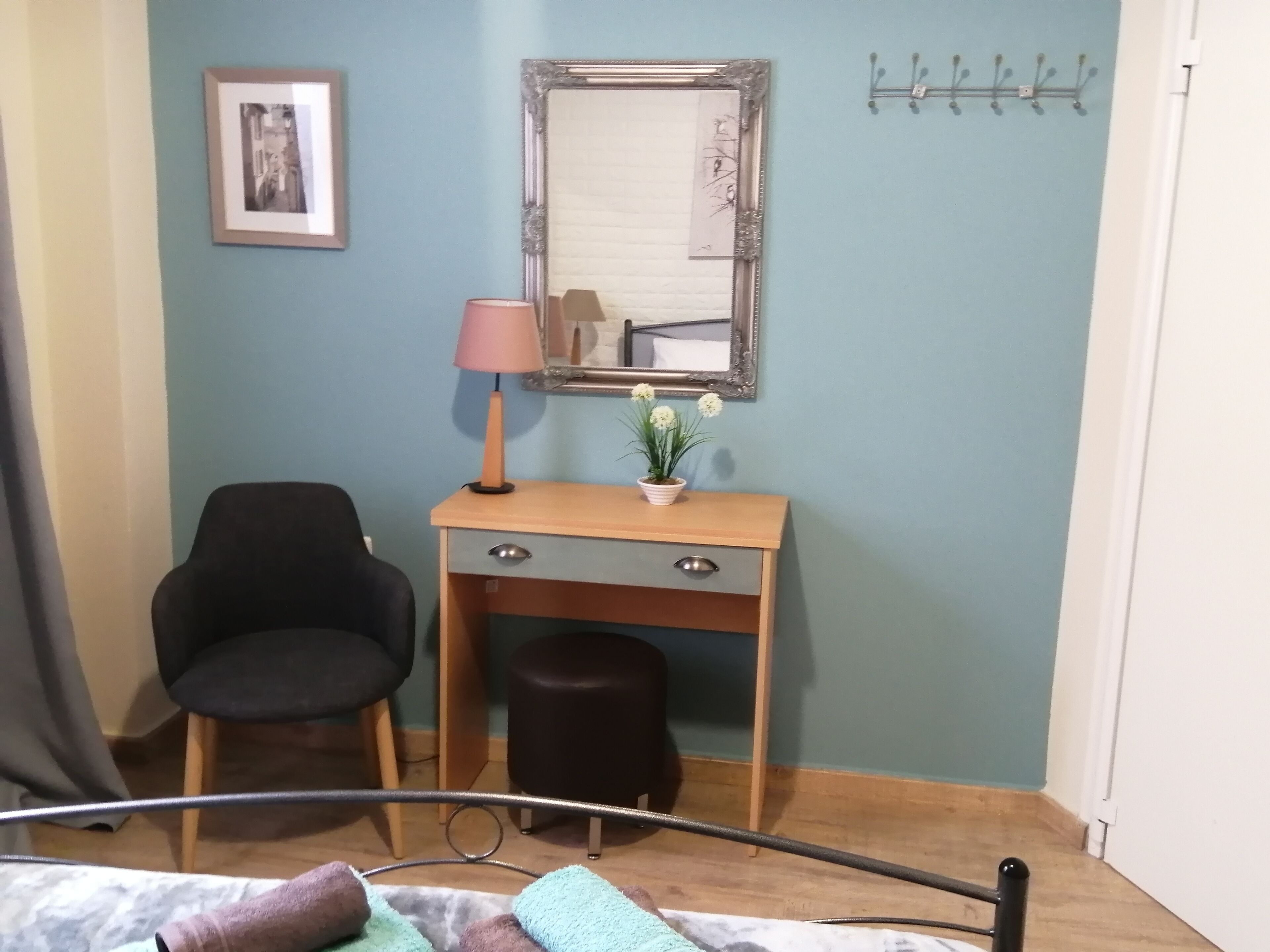 Een slaapkamer met een bed, een bureau met lamp, een stoel en een spiegel aan de muur.