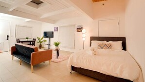 Une chambre moderne avec un grand lit, un canapé, une télévision et un coin repas.
