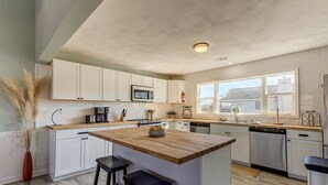 A modern kitchen with white cabinets, a wooden island, and stainless steel appliances.