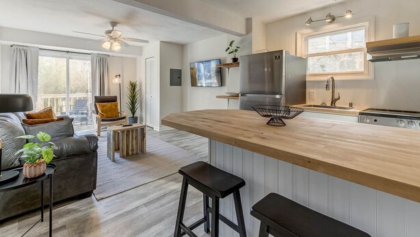 A modern kitchen with a wooden island, stainless steel appliances, and a large window.