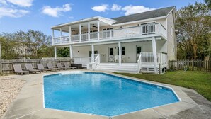 A two-story house with a swimming pool, a fenced backyard, and a wooden deck.