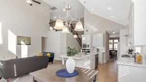 Un espacio habitable moderno y abierto, con una mesa de comedor, sofá y cocina al fondo.