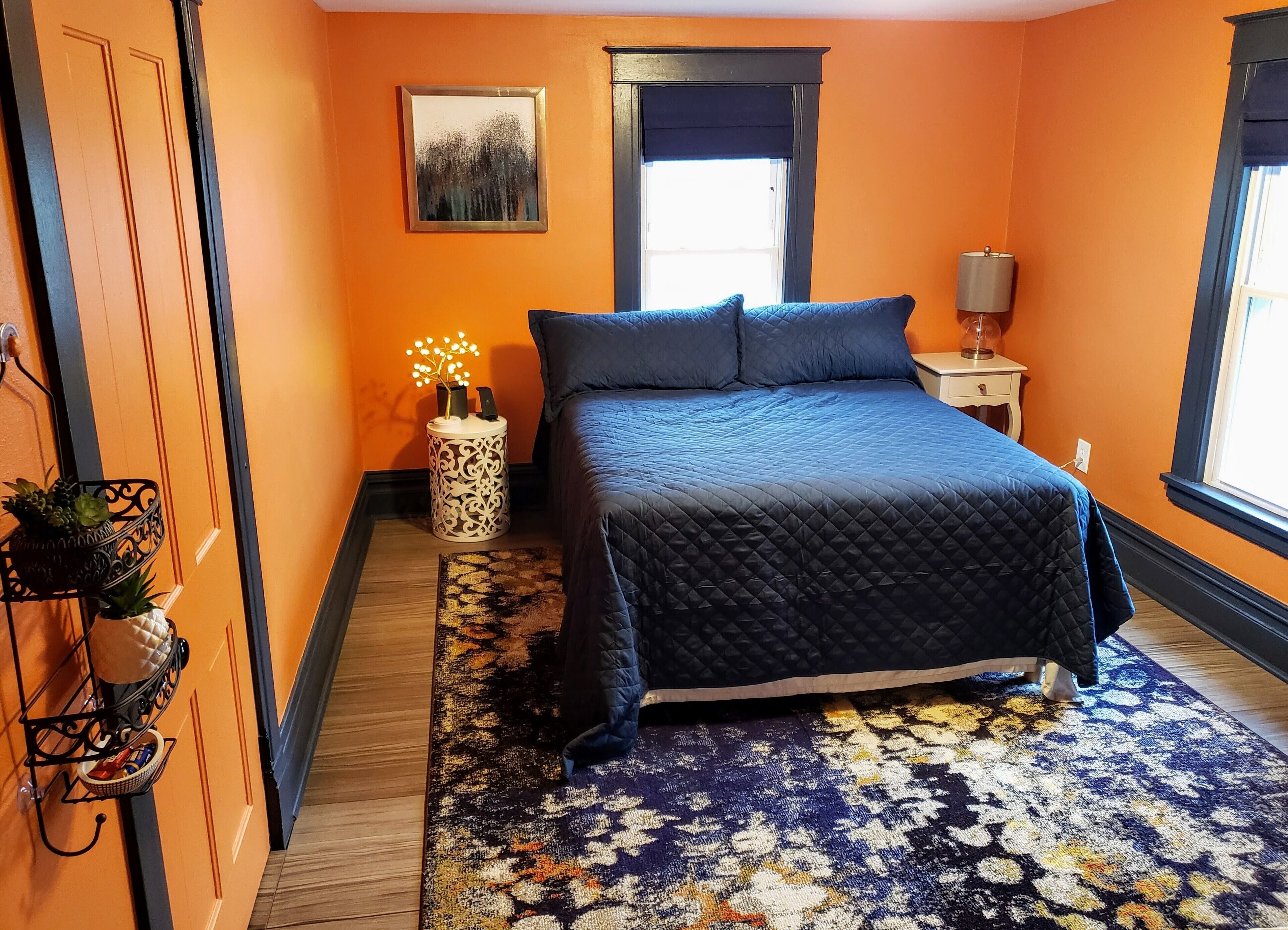 Un dormitorio con cama, mesita de noche, ventana y puerta.