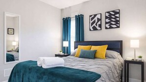 Un dormitorio moderno con una cama, una mesita de noche, un espejo y dos lámparas de pared.