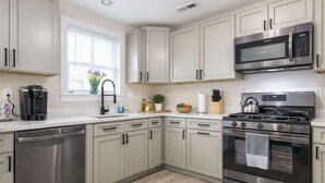 Une cuisine moderne dotée d’appareils électroménagers en acier inoxydable, de meubles de couleur claire et d’une fenêtre offrant une belle vue.
