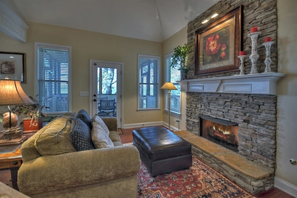 A cozy living room with a stone fireplace, a comfortable sofa, and a patterned rug.