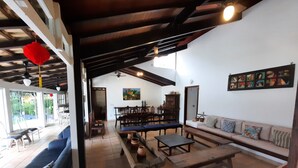 Un'ampia zona giorno con soffitto alto, travi in legno, un'area pranzo e un divano.