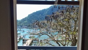Una stanza con vista su un porto turistico e un paesaggio montuoso.