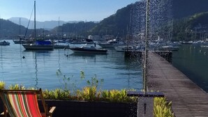 Un patio sul lungomare con un pontile in legno, un'amaca colorata e una fontana.