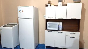 Eine kleine Küche mit Kühlschrank, Mikrowelle und einer Waschmaschine.