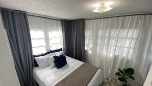 Ein Hotelzimmer mit Bett, Vorhängen, Deckenventilator und einer Topfpflanze.