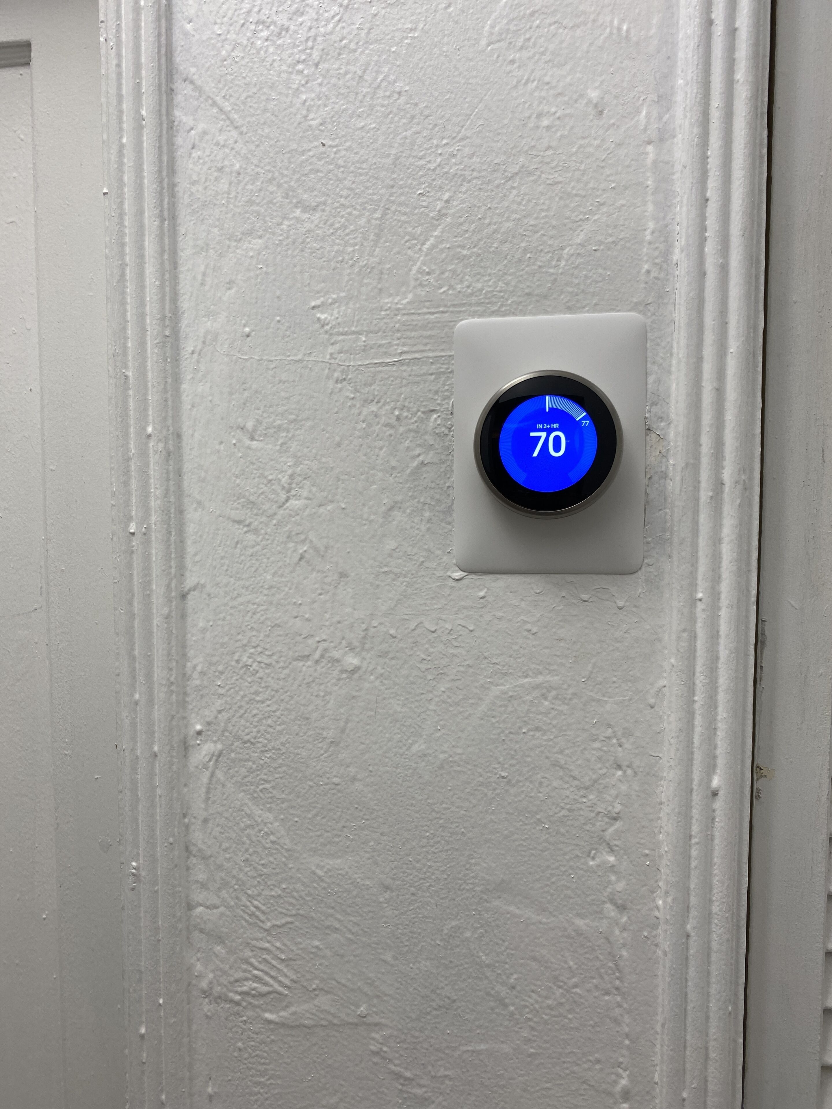 Termostato en una pared blanca que indica una temperatura de 21 grados Celsius.