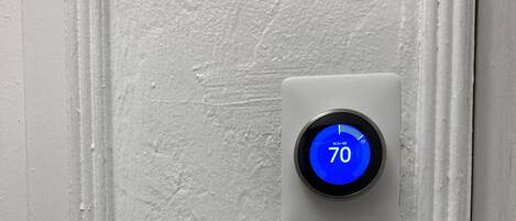 Termostato en una pared blanca que indica una temperatura de 21 grados Celsius.