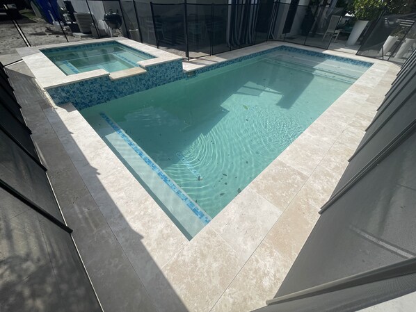 A rectangular outdoor swimming pool with a tiled edge and a smaller section for children.