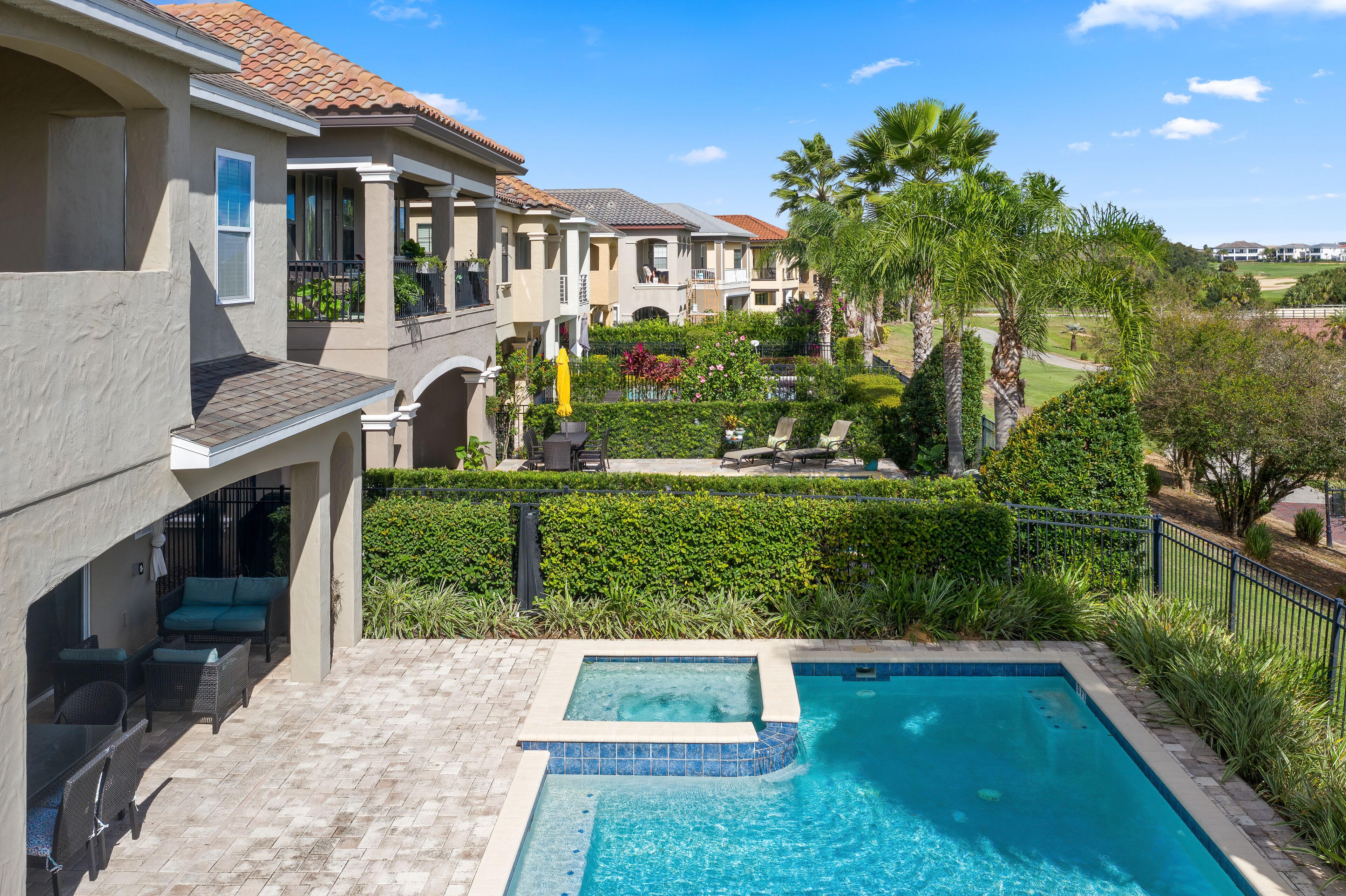 Zona residencial con piscina, mobiliario de patio y un jardín bien cuidado.