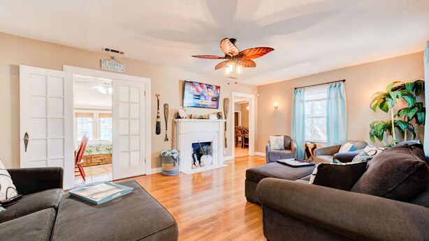 A spacious living room with a fireplace, a ceiling fan, and a television.