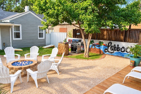 A backyard with a barbecue grill, outdoor seating, and a mural.