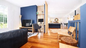 Un salon moderne avec un canapé noir, une table basse en bois et un téléviseur.