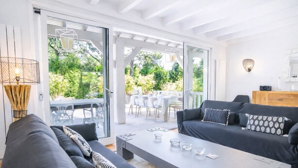Un salon moderne comprenant un ensemble de canapés, une table basse et donnant sur un espace patio extérieur.
