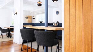 Une cuisine moderne avec des meubles en bois, un îlot central, des tabourets de bar noirs, des luminaires suspendus et un tapis à motifs de girafe.