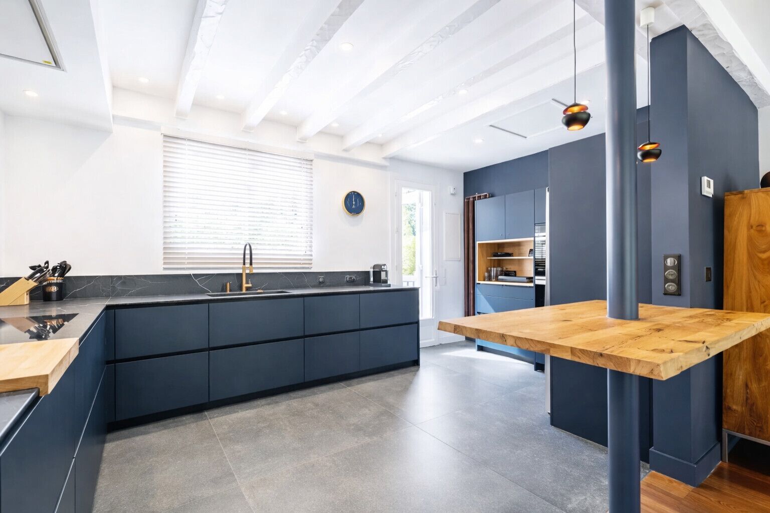 Una cocina moderna con una isla central, muebles oscuros y una mesa de comedor de madera.