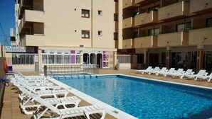 En swimmingpool med solstolar och en snackbar.