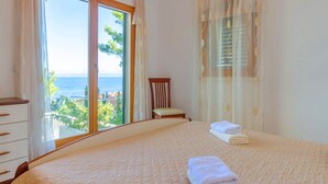 A bedroom with a large bed, a chair, and a view of the sea through a window. - Seafront Holiday Home Marija-Three Bedroom Holiday Home with Sea View (Prigradica)