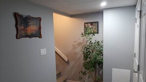 Un couloir avec un escalier, une plante en pot et une porte.